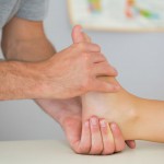 Physiotherapist controlling patients foot in bright office